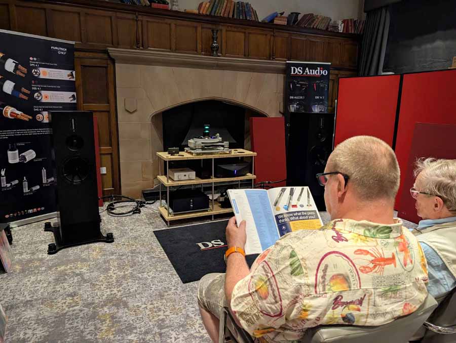 HiFi NETWORK
Victor, from HiFi Network, talked me through this cool, ultra-simple system. The stars of the show were a pair of ELAC Debut Reference 3.0 (£1399), which they claim, “builds on the success of Debut 3.0 with redesigned driver technology, refined cabinet design, and a true 3-way floorstanding architecture.” Also in the range, both with 2-way bass reflex, are: standmounts (£749) and a centre channel speaker (£449). These come in five different finishes, including: black, green, satin white, titanium, and walnut.
An AVM CS30.3 streaming amplifier was doing an admirable job of driving the ELACs, even with some laid back, and gentle smooth jazz. Having reviewed the Carina BS 243.4 bookshelf loudspeakers from the brand, I can testify their speakers benefit from an amp that can drive them, to bring out their best. This amp had it covered, with ease, and was also a lovely-looking box in chrome finish (£3700). Also on display, but not in the system at the time I was in the room, was an Inspiration C2.3 streaming amp, in a gorgeous gold satin colour. The option of this finish is exclusive to this model but doesn’t carry any additional premium. Gorgeous kit.