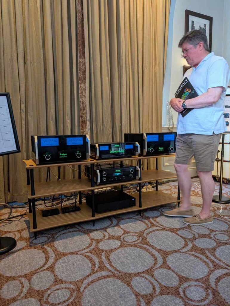 HiFi NETWORK
Victor, from HiFi Network, talked me through this cool, ultra-simple system. The stars of the show were a pair of ELAC Debut Reference 3.0 (£1399), which they claim, “builds on the success of Debut 3.0 with redesigned driver technology, refined cabinet design, and a true 3-way floorstanding architecture.” Also in the range, both with 2-way bass reflex, are: standmounts (£749) and a centre channel speaker (£449). These come in five different finishes, including: black, green, satin white, titanium, and walnut.
An AVM CS30.3 streaming amplifier was doing an admirable job of driving the ELACs, even with some laid back, and gentle smooth jazz. Having reviewed the Carina BS 243.4 bookshelf loudspeakers from the brand, I can testify their speakers benefit from an amp that can drive them, to bring out their best. This amp had it covered, with ease, and was also a lovely-looking box in chrome finish (£3700). Also on display, but not in the system at the time I was in the room, was an Inspiration C2.3 streaming amp, in a gorgeous gold satin colour. The option of this finish is exclusive to this model but doesn’t carry any additional premium. Gorgeous kit.